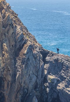 Shellfish catcher ascending the cliff of Cabo Sardao coast, Ponta do Cavaleiro, Sao Teotonio, Portugal