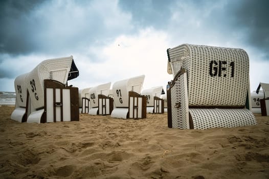 Roofed wicker beach chairs at the baltic sea beach, coast at the island of Usedom in Germany, storm and rain over the brackish water, high waves, storm warning
