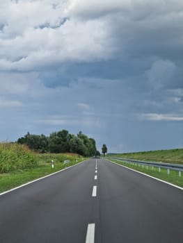 POV- Driving on a straight road, cloudy sky and green surroundings