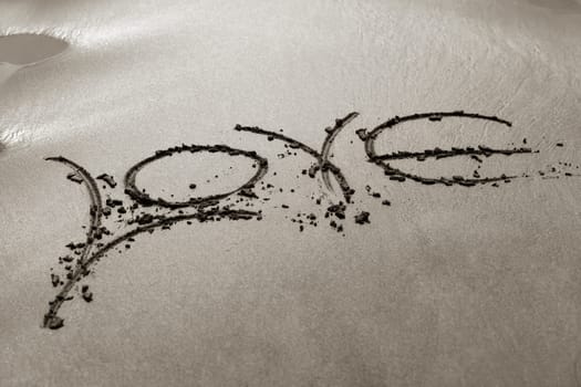 The word "love"" is written by someone on sand"