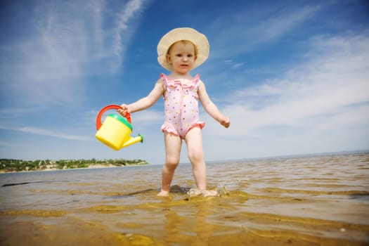 small girl with watering-pot on the seashore