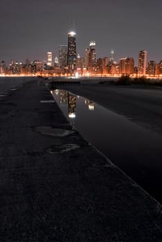 Chicago night skyline with partial beach and water reflections