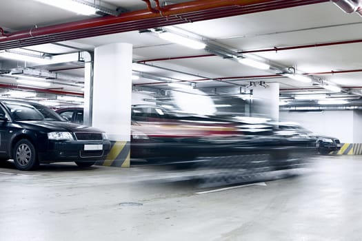 The shined underground garage with the moving cars and parked cars