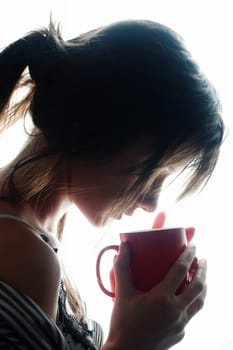 Young woman enjoying her coffee near the window