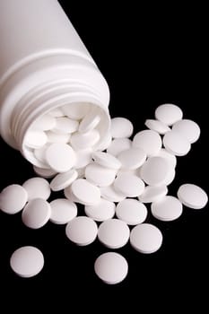 bottle with white pills on black background