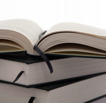 Open book on top of other books isolated on white background