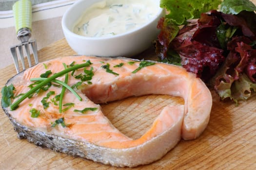 grilled salmon steak on wooden board with salad