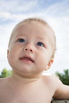 Happy naked boy in outdoor conditions looks upward