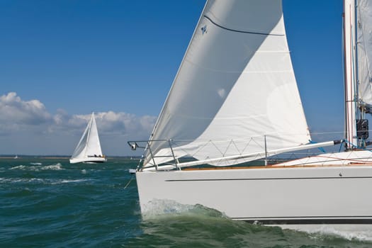 Two beautiful white yachts sailing on a bright sunny day
