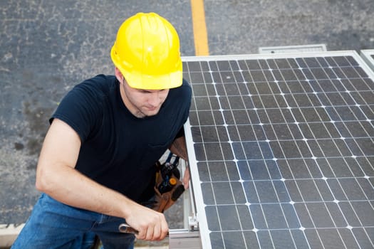 Electrician installs solar panels on the side of a building.