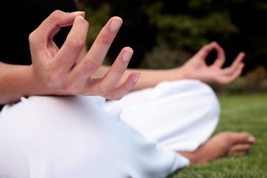 Woman sitting down meditating on a lawn