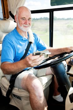 Senior man using GPS navigation to drive his motor home.