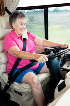 Senior woman enjoys driving her luxury motor home.