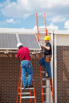 Two workers installing solar panels on the side of a building.  Vertical with room for text.