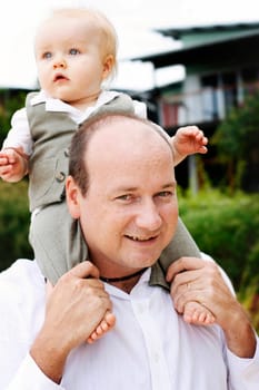 A close-up portrait of a happy father and son enjoying time together outdoors with the father carrying his son on his shoulders.