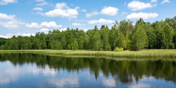 Reservoir at the red moor in the high Rhoen, Hesse, Germany. With blue sky and white clouds and reflection in the water
