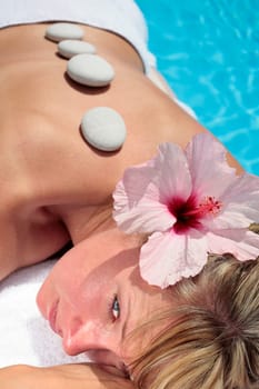 Woman with massage stones by a blue pool