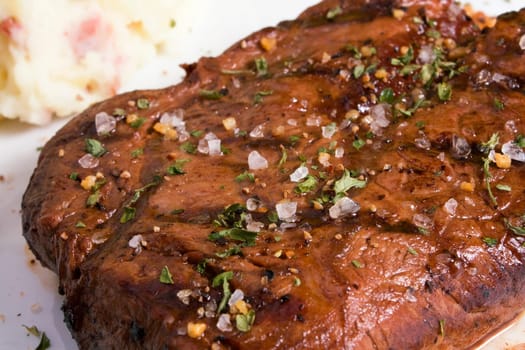 Grilled steak seasoned with coarse salt and herbs.