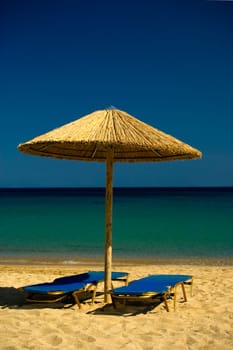 Two lounge chairs and umbrella  on Paradise Beach , Mykonos , Greece.