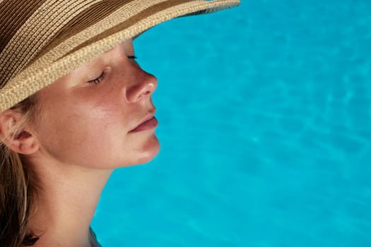 Woman sunbathing by blue swimming pool