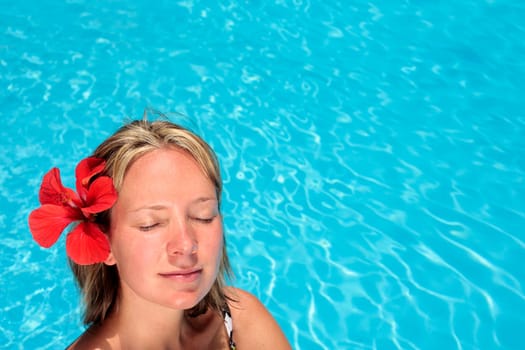 Woman sunbathing by blue swimming pool