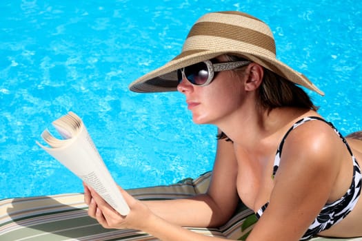 Woman reading by the swimming pool