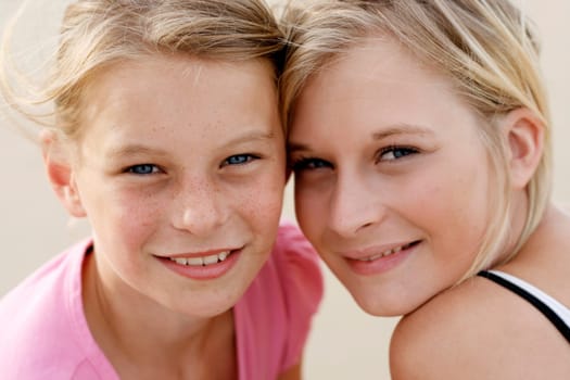 A portrait of two happy young sisters together outdoors.