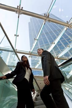 A young make and female exuctive ride an escalator together in a modern hi-tech city setting