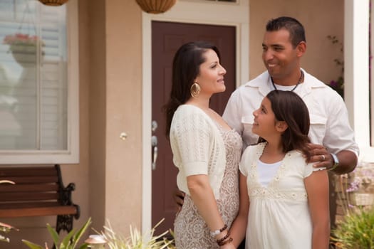 Small Hispanic Mother, Father and Daughter in Front of Their Home.
