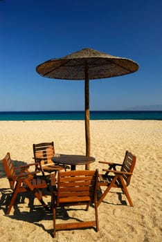 Chairs, table and grass-umbrella on the  beach.Mykonos. Greece.