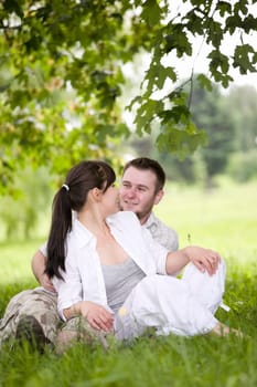 happy couple together sitting on grass