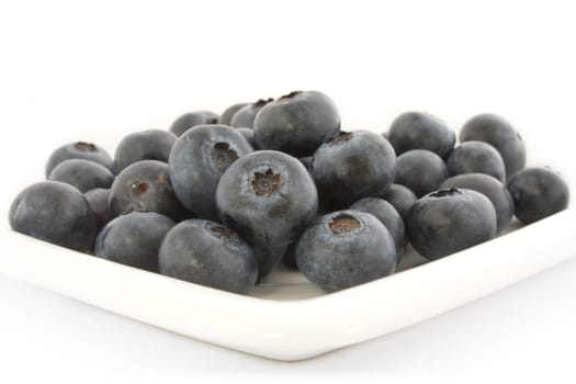 A plate with fresh blueberries isolated on white background, with shadow.