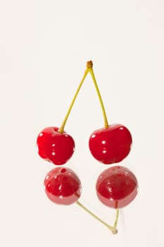 food series: two cherries on reflective sutface