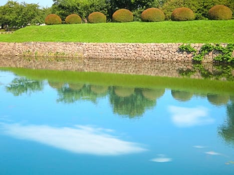 Japanese lake with stone wall and garden