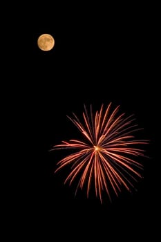 A red and yellow fireworks bursting near the moon.