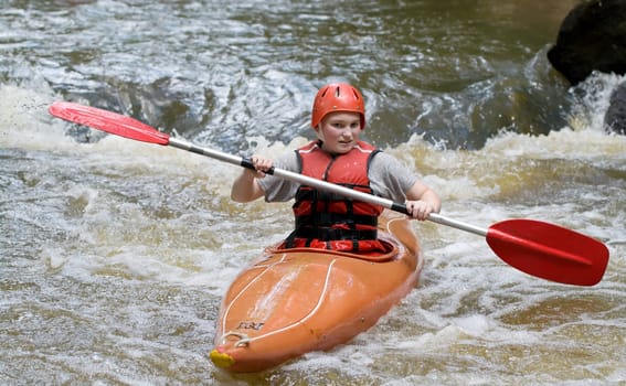 image of a teenage girl doing whitewater kayaking down a river