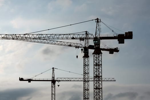 Tower crane silhouettes against cloudy sky