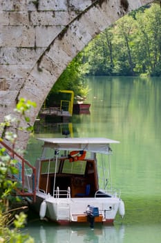 A small boat under an old stone bridge