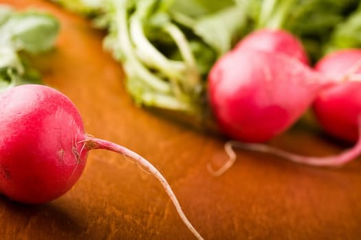 radish on a wood cutting board leaves and roots