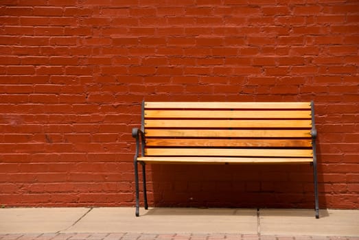 A bench beside a red brick wall.