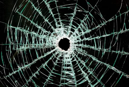 There is a broken car glass of windscreen with hole in picture center, looks like black space