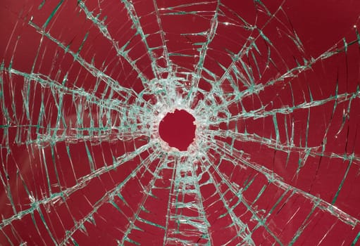 There is a broken car glass of windscreen with hole in picture center