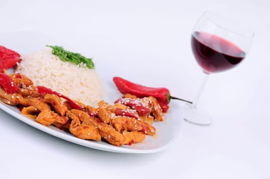 A plate rice and  special chicken with blurry a glass of wine