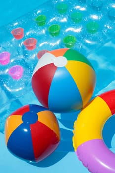 Beach balls, a rubber ring and a lilo in a nice blue pool