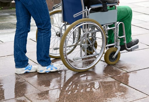 Woman pushing man in wheelchair along street