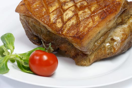Crunchy pork roast on a plate over white background
