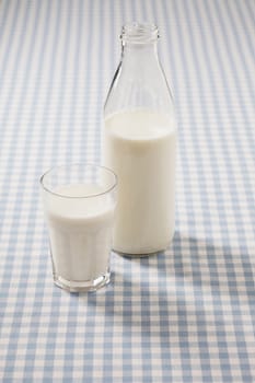 Milk in a glass and a bottle on a plaid tablecloth