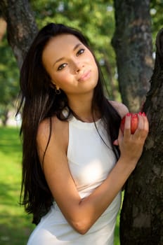 Beautiful young women holding a red apple in the garden
