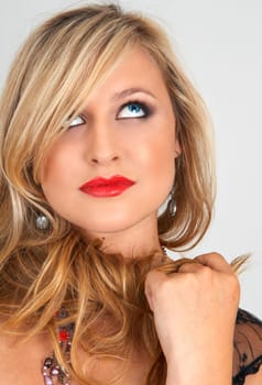 Portrait of a beautiful blonde woman with light blue eyes and evening make-up on grey background