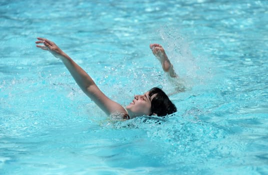Child Swimming in a Pool With Arm and Leg Out in Mid Stroke